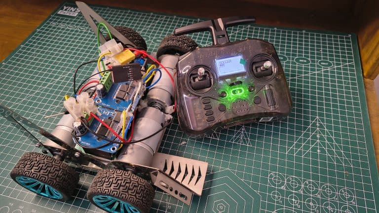 Custom 600RPM high-speed soccer robot with RadioMaster RC controller on a green cutting mat, featuring high-torque DC motors and dual motor drivers.
