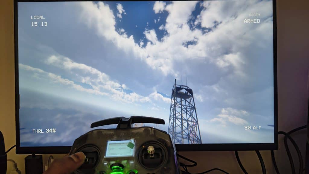 High-angle shot of a drone simulator screen displaying flight telemetry like altitude and throttle percentage, being controlled by a RadioMaster Pocket transmitter in a home office setup.