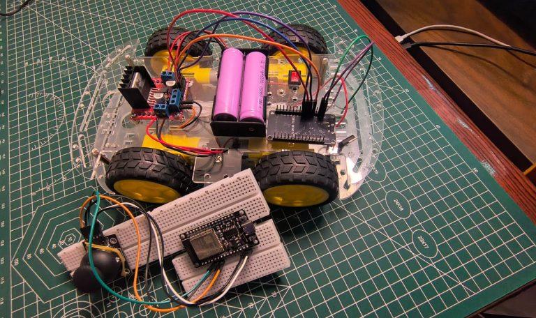 A top-down view of a DIY ESP32 RC car project featuring a clear acrylic chassis with four yellow wheels, an L298N motor driver, and a 18650 battery pack. In the foreground, a second ESP32 microcontroller is mounted on a white breadboard and wired to a joystick module, serving as the remote controller for the build.
