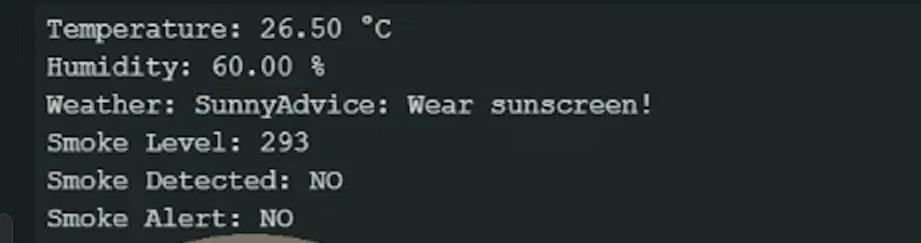 Build Your Own ESP32 DIY Weather Station: Track Temperature, Humidity & Air Quality 8 A digital readout from a diy weather station project showing environmental data. The text on a dark background displays a temperature of 26.50°C, humidity at 60.00%, weather as "Sunny," and an advice note saying "Wear sunscreen!". Below this, it lists a smoke level of 293 with "Smoke Detected: NO" and "Smoke Alert: NO".